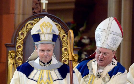 Newly ordained Bishop Edward B. Scharfenberger, left, is helped with his crosier by Cardinal Timothy Dolan, April 10, 2014, during his installation as 10th bishop of the Albany Diocese in New York. 